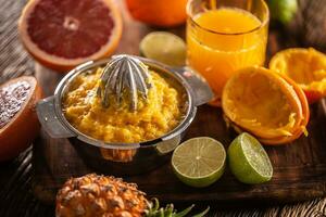 Squeezed orange pulp in a juicer with cfreshly cut citruses and a glass of juice photo