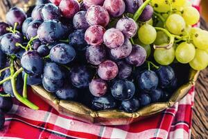 Grape. Bunch of multicolored grapes in retro bowl on old oak table photo