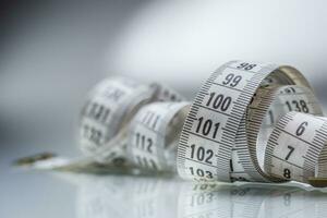 Curved measuring tape. Measuring tape of the tailor. Closeup view of white measuring tape photo