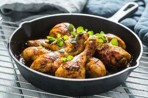 Roasted chicken legs in pan with herbs - close up photo