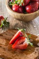 Juicy washed strawberries in wooden bowl on kitchen table photo