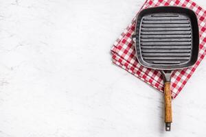 Empty grill pan on marble table with red tablecloth - top of view photo