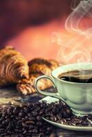 Coffee. Cup of coffee croissants and coffee beans. Vintage cup and old oak table photo