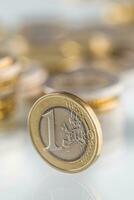 Euro coin balances on another coin and several loose coins photo