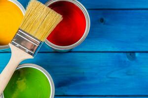 Paint cans color palette, cans opened with brushes on blue table photo