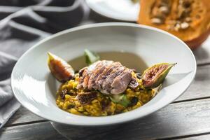 Pumpkin risotto roasted duck breast figs zucchini and min leaves. italian or mediterranean cuisine photo