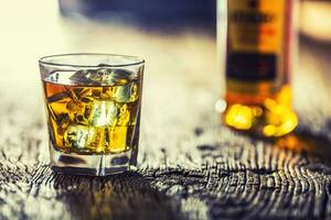 Whiskey. Whiskey drink with ice cubes on old rustic oak table photo