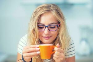 taza de café en mano de contento joven mujer. atractivo niña Bebiendo Mañana té foto