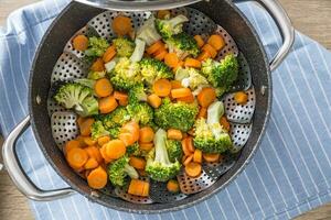 Steamed mixed vegetable in black pot. Healthy vegetable concept photo