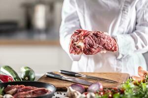 Detail of a chef holding big chunk of red meat in hands photo