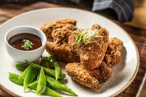 Fried chicken wings with sugar peas and herbs photo