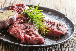 Beef meeat Rib-Eye steak wit rosemary salt and pepper on black plate photo