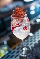 Gin tonic cocktails in wine glass with chili on bar counter in pup or restaurant photo