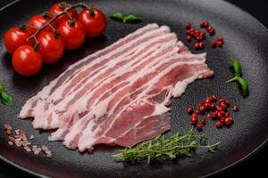 Fresh raw bacon cut into slices with salt, spices and herbs photo