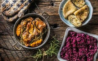 Roasted duck legs in pan with oranges herbs red cabbage and potato pankaces photo