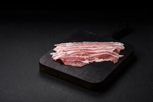 Fresh raw bacon cut into slices with salt, spices and herbs photo