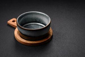 Empty round ceramic bowl on a wooden cutting board in brown color photo