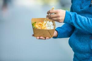 Young mans hands holding lunch in a box of recycled paper photo