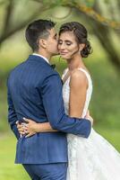 Just married couple hold each other with eyes closed and smiles on their faces photo