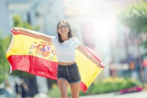 Happy girl tourist walking in the street with spanish flag photo