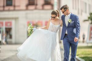 un joven sólo casado Pareja caminando felizmente en el pueblo en Boda batas con un hermosa ramo de flores foto