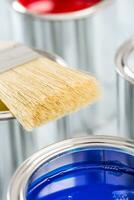 Close-up brush lying on multicolored paint cans. photo