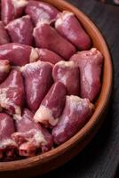 Fresh raw chicken or turkey hearts in a ceramic plate with salt, spices and herbs photo