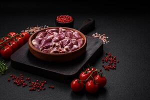 Fresh raw chicken or turkey hearts in a ceramic plate with salt, spices and herbs photo