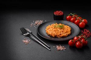 Delicious fresh pasta consisting of thin noodles, red pesto rosso sauce with spices and herbs photo