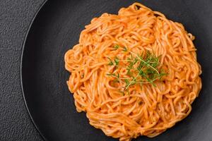 Delicious fresh pasta consisting of thin noodles, red pesto rosso sauce with spices and herbs photo