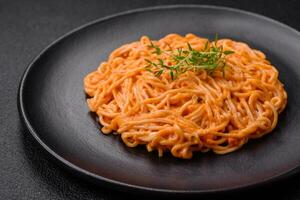 Delicious fresh pasta consisting of thin noodles, red pesto rosso sauce with spices and herbs photo