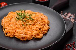 Delicious fresh pasta consisting of thin noodles, red pesto rosso sauce with spices and herbs photo