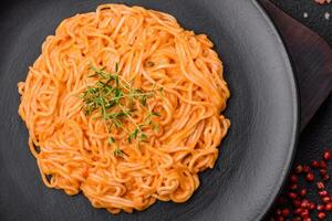 Delicious fresh pasta consisting of thin noodles, red pesto rosso sauce with spices and herbs photo