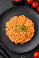 Delicious fresh pasta consisting of thin noodles, red pesto rosso sauce with spices and herbs photo