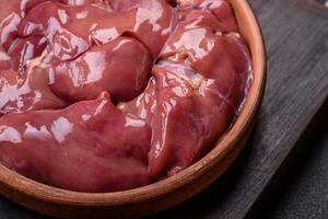 Fresh raw chicken or turkey liver in a ceramic plate with salt, spices and herbs photo