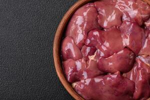 Fresh raw chicken or turkey liver in a ceramic plate with salt, spices and herbs photo