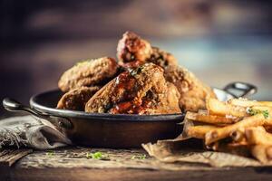 Fried chicken wings with fries on table in pub. photo