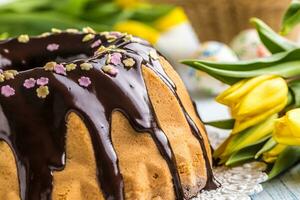 delicioso fiesta eslovaco y checo pastel babovka con chocolate vidriar. Pascua de Resurrección decoraciones - primavera tulipanes y huevos foto