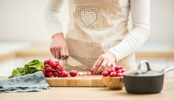 mujer rebanar Fresco rábano a hogar en cocina foto