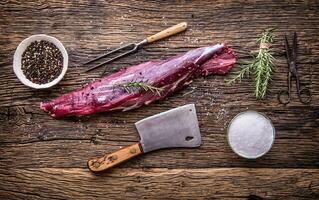 Raw beef meat. Raw beef tenderloin steak on a cutting board with rosemary pepper salt in other positions. photo