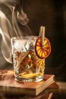 Smoked old fashioned rum cocktail with cubes of ice around on a dark background. photo