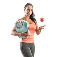 Slim and good-looking brunette tosses an apple and holds weighing scale in her other hand photo