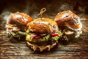 Front view on three large, beef salmon and kebab burgers stuffed with fresh vegetable salad and dressing photo