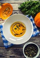 Pumpkin cream soup with seeds and parsley on kitchen table - Top of view photo