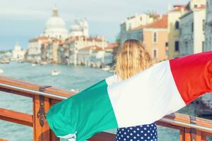 turista mujer con italiano bandera en el puente en grandioso canal en Venecia - Italia foto