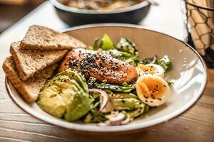 sano hoja ensalada preparado con palta, huevos, sésamo y A la parrilla salmón foto