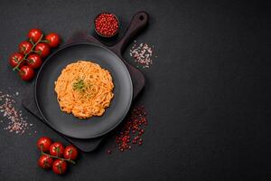 Delicious fresh pasta consisting of thin noodles, red pesto rosso sauce with spices and herbs photo