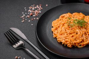 Delicious fresh pasta consisting of thin noodles, red pesto rosso sauce with spices and herbs photo