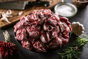 Bowl of raw cuts of beef with herbs and garlic ready for making a hearty soup or stew photo