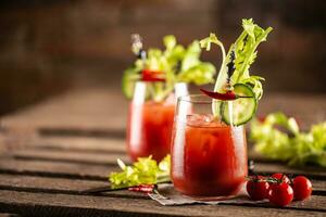 Bloody or virgin mary cocktail served in a cup with celery sticks and cherry tomatoes photo